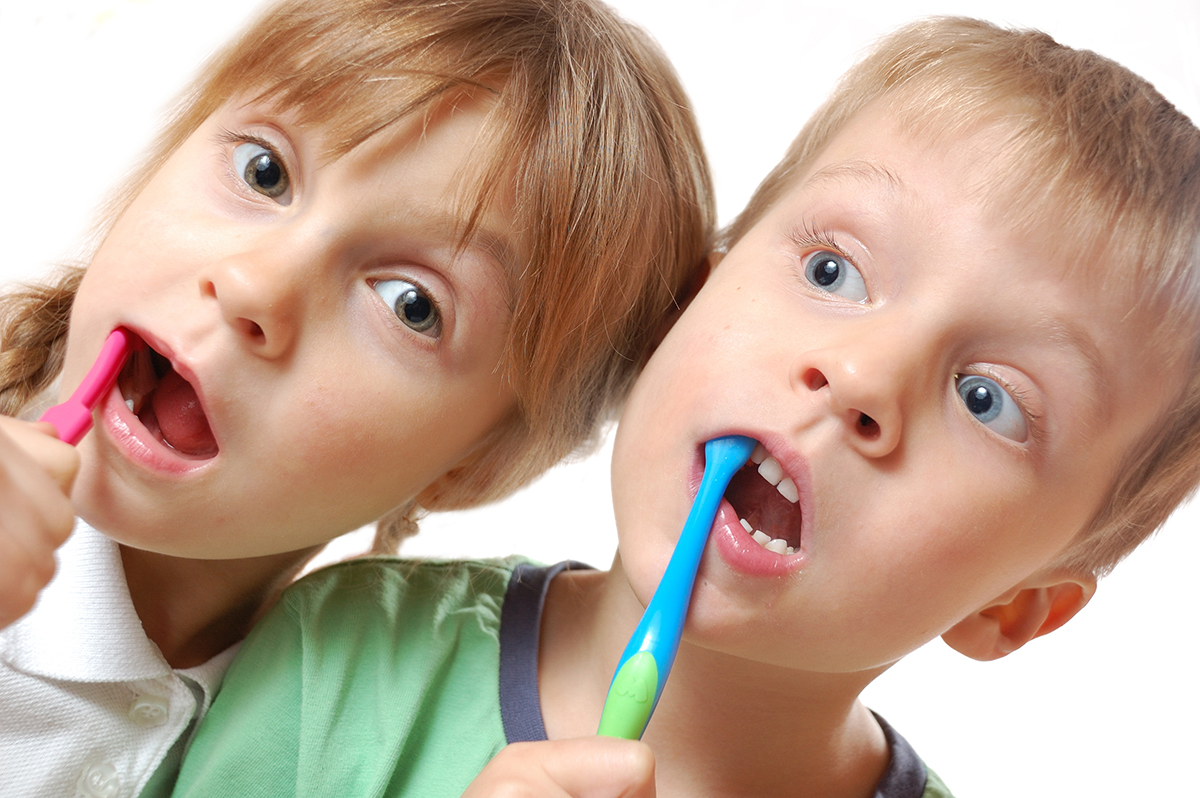 two cute kids brushing their teeth over white background