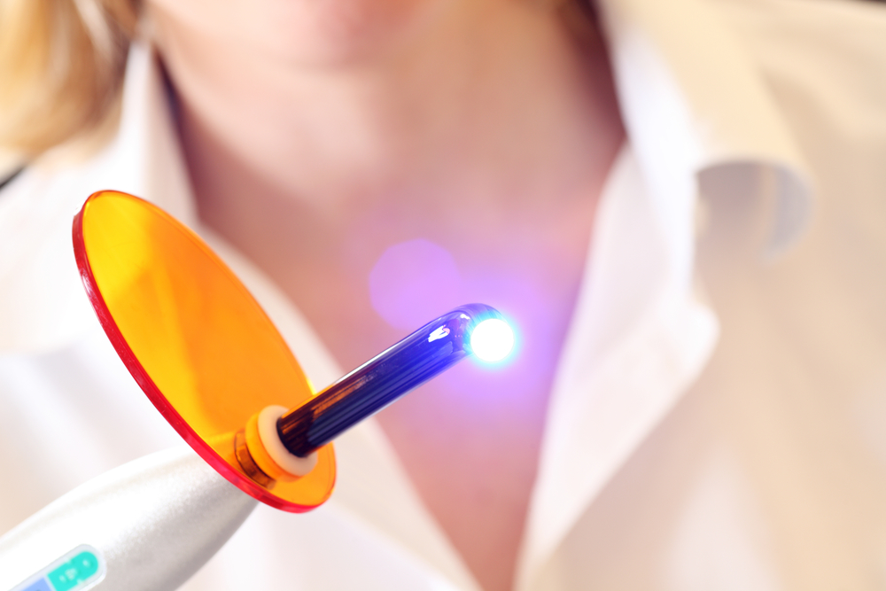 Dentist holds a lit dental curing UV light